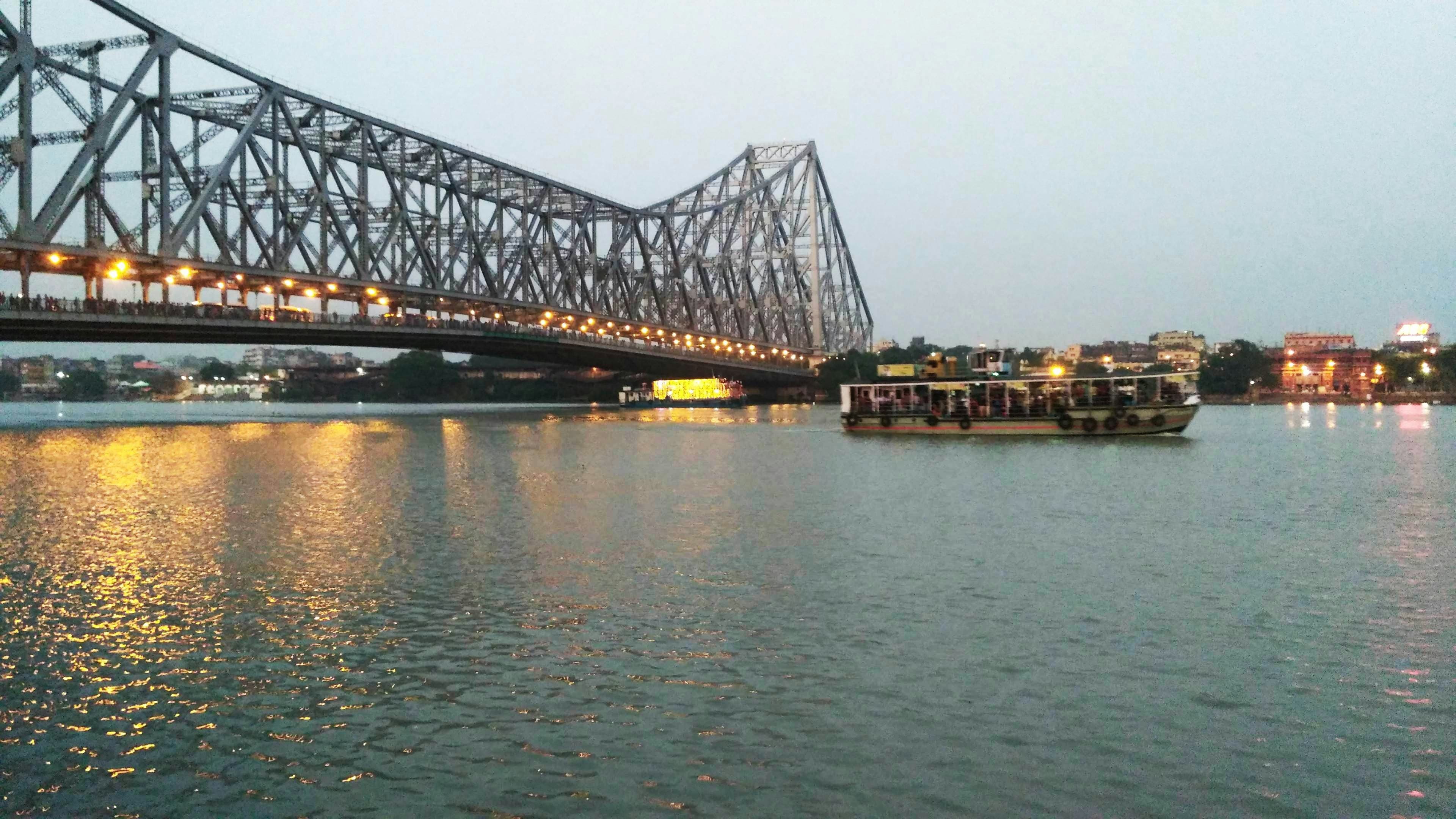 Cruise boat passing Howrah Bridge at dusk